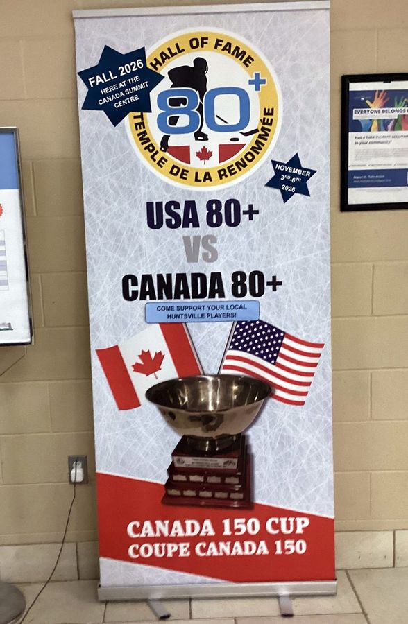 Roll-up banner in an arena lobby: 80+ Hockey Hall of Fame crest, USA 80+ vs Canada 80+, Canadian and American flags behind the trophy, and Canada 150 Cup, Coupe Canada 150.